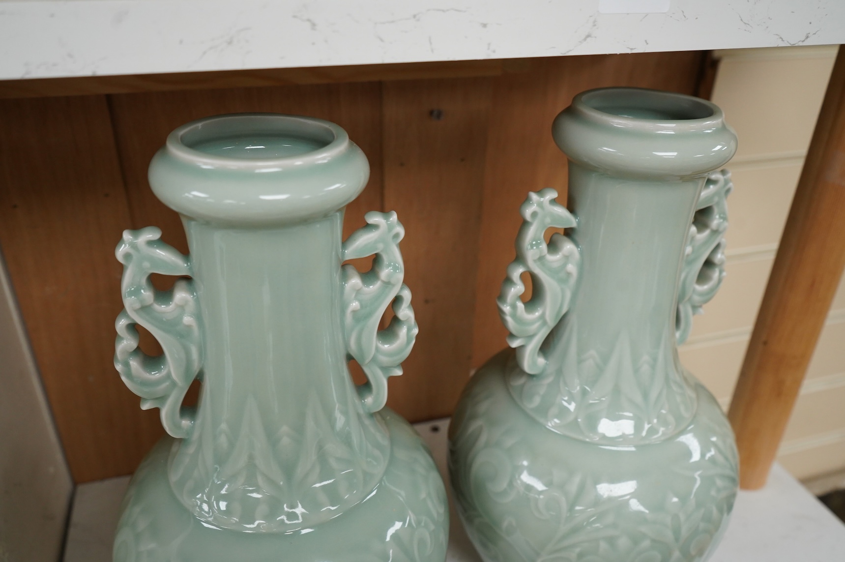 A pair of Chinese celadon glazed vases, decorated in low relief, 32cm high
